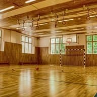 Turnhalle mit Holzdecke, Ringen und Handballtor